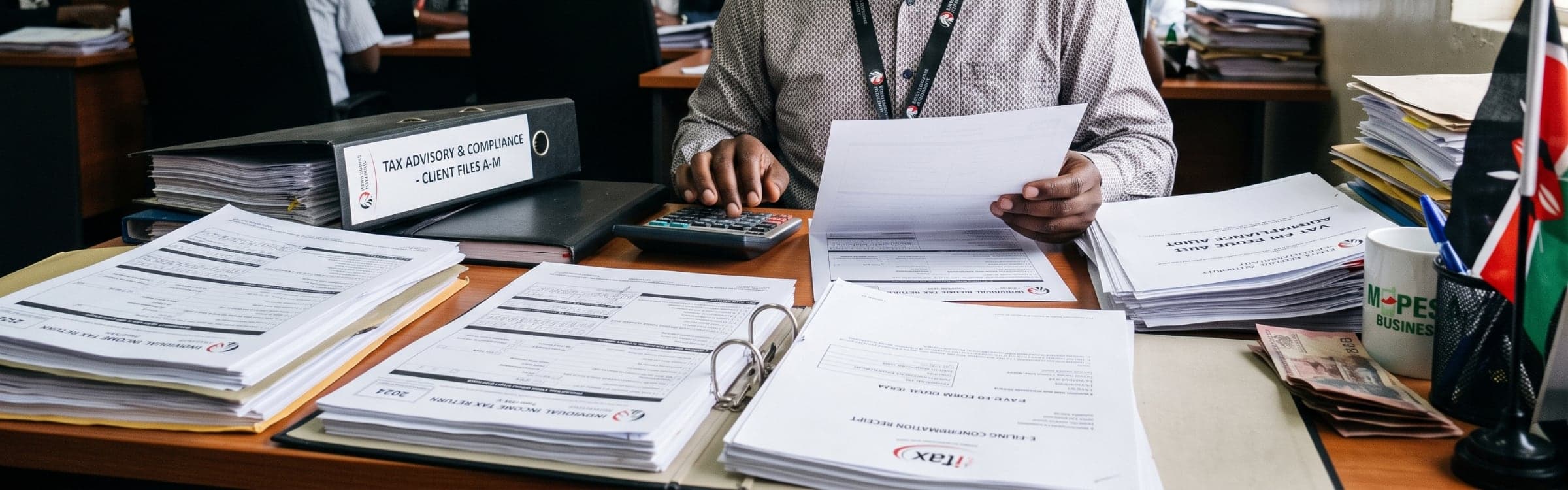 Stacks of filed returns and ring binders on an office desk beside a calculator.